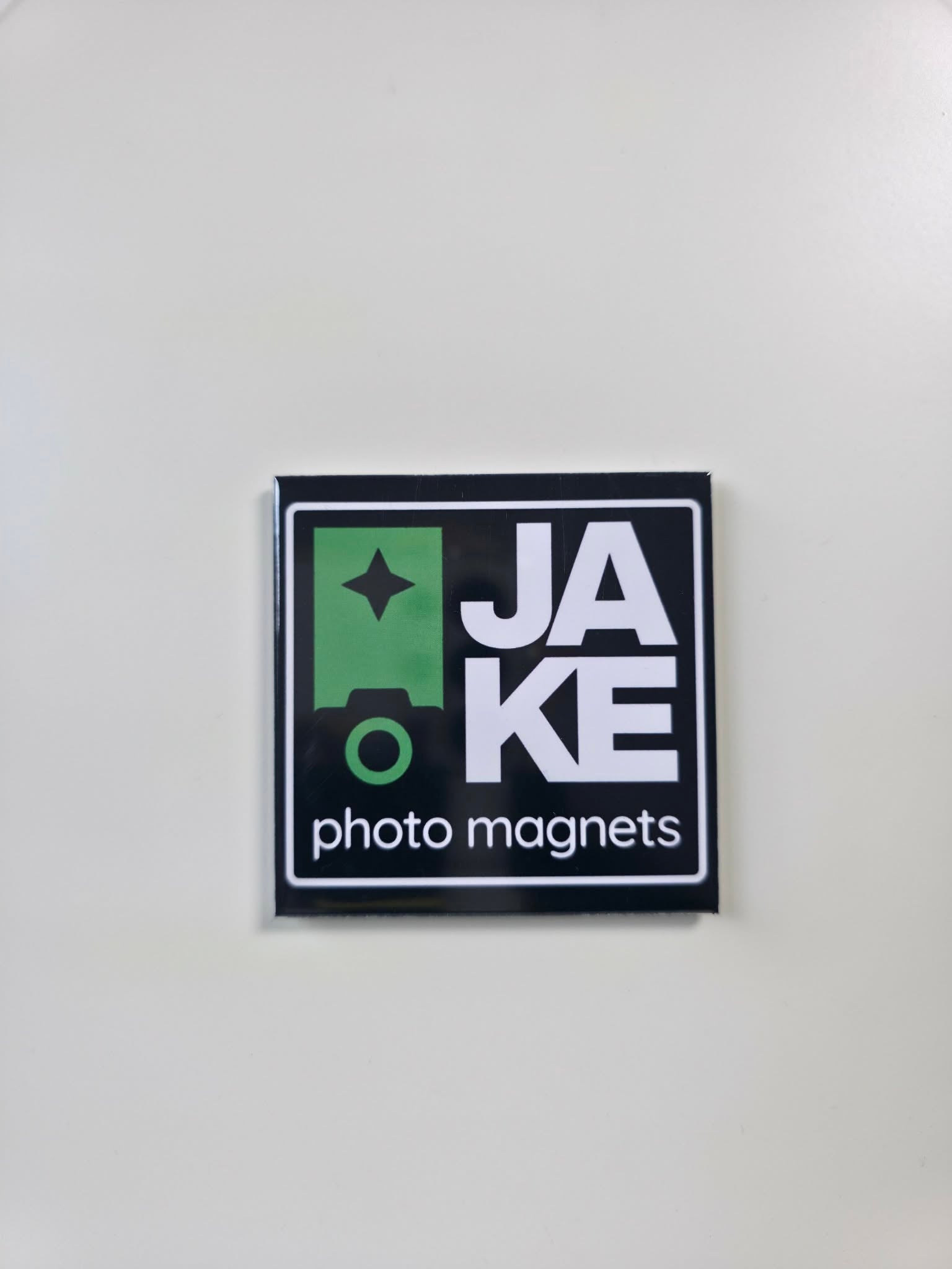 Square magnet with 'JAKE photo magnets' text on a white background