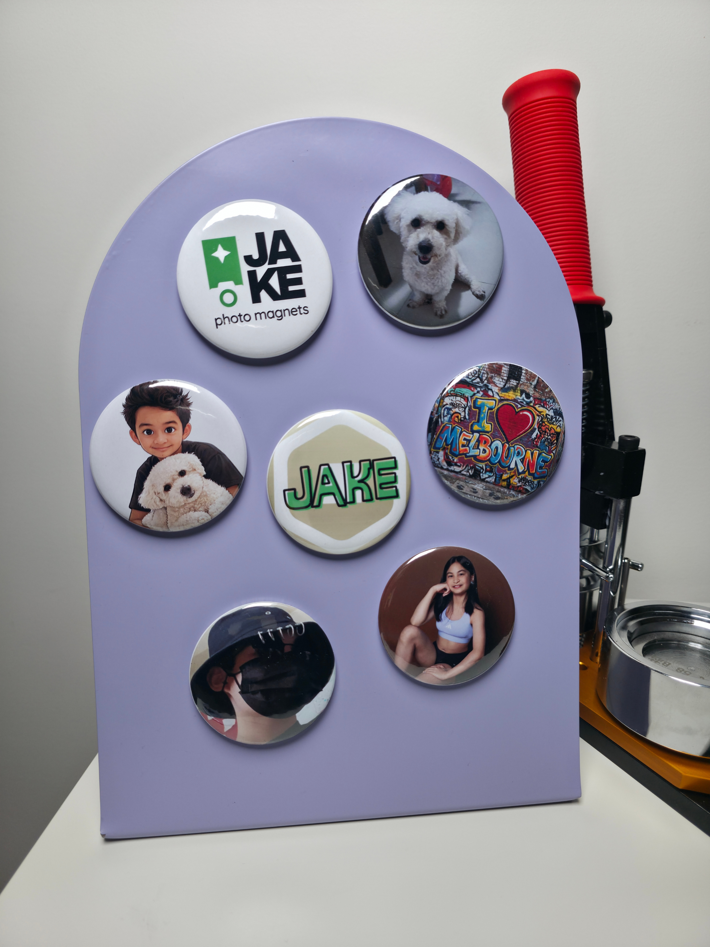 Purple board with various round magnets featuring images and text, including a dog and 'JAKE'.