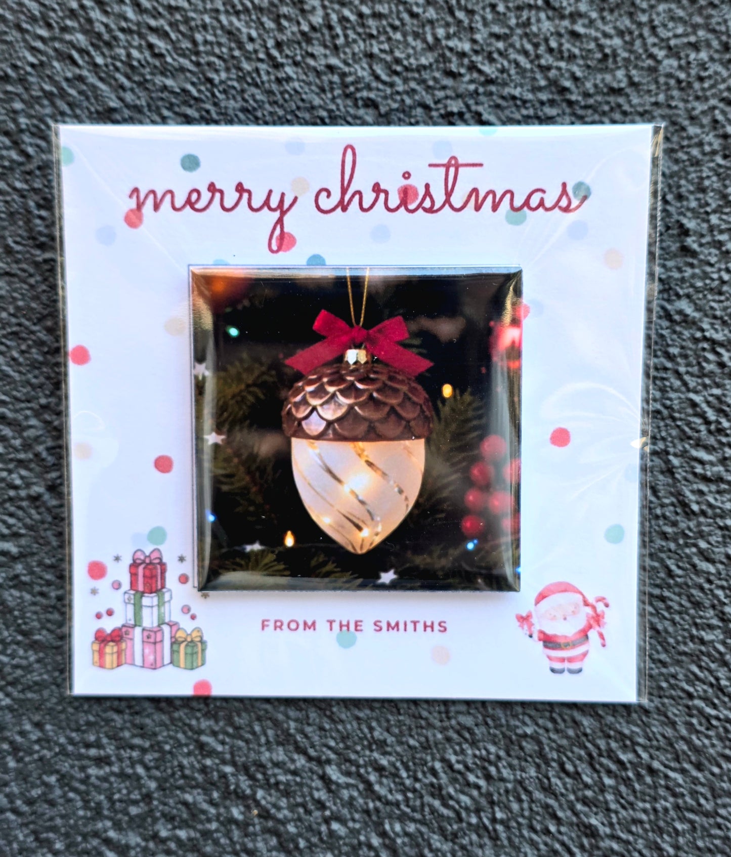 Christmas ornament packaging with 'merry christmas' text and decorative elements on a textured gray background.