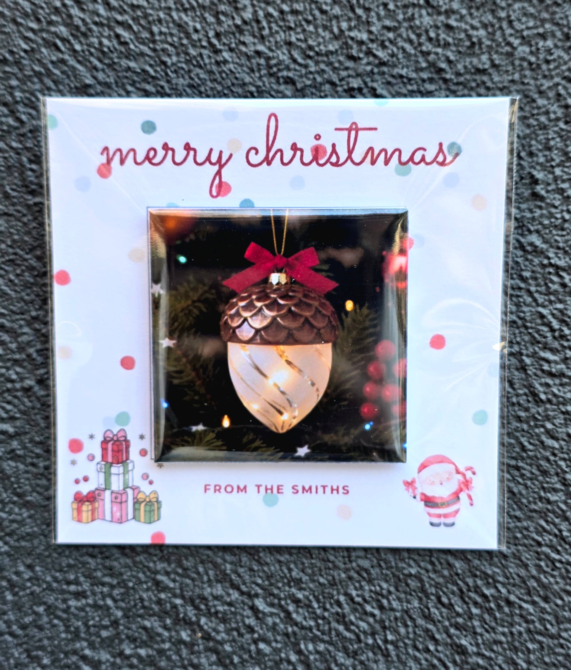 Christmas ornament packaging with 'merry christmas' text and decorative elements on a textured gray background.