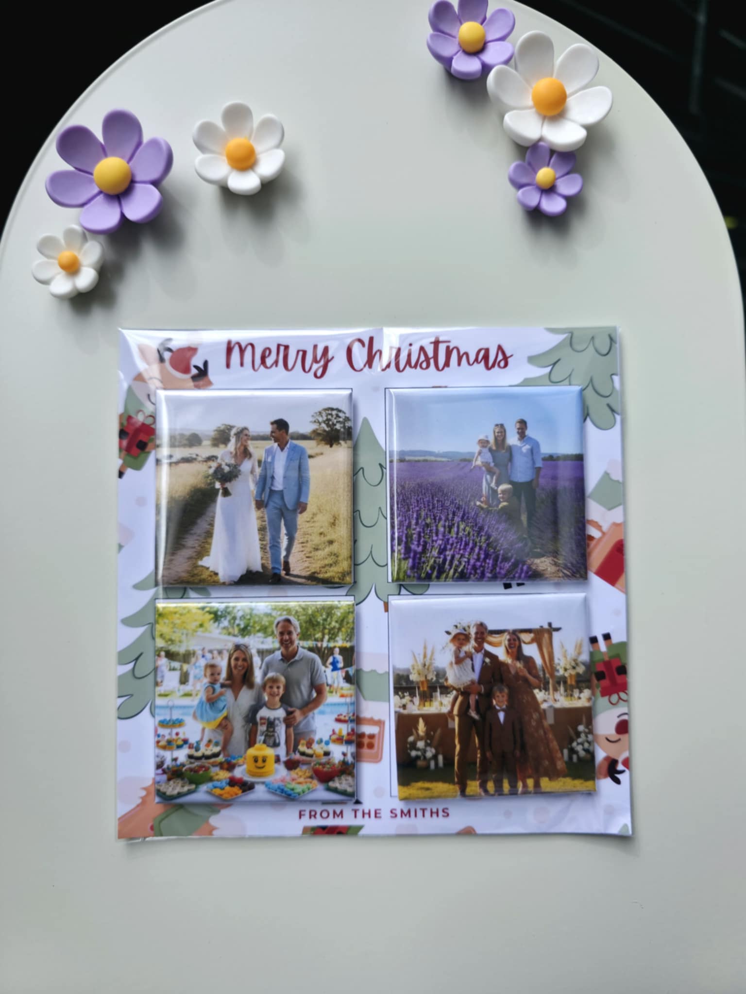Personalized Christmas card with family photos and decorative flowers on a white surface