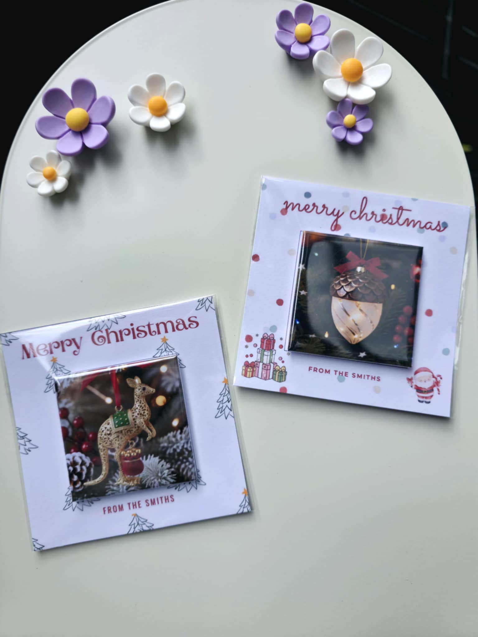 Two Christmas cards with decorative flowers on a white surface