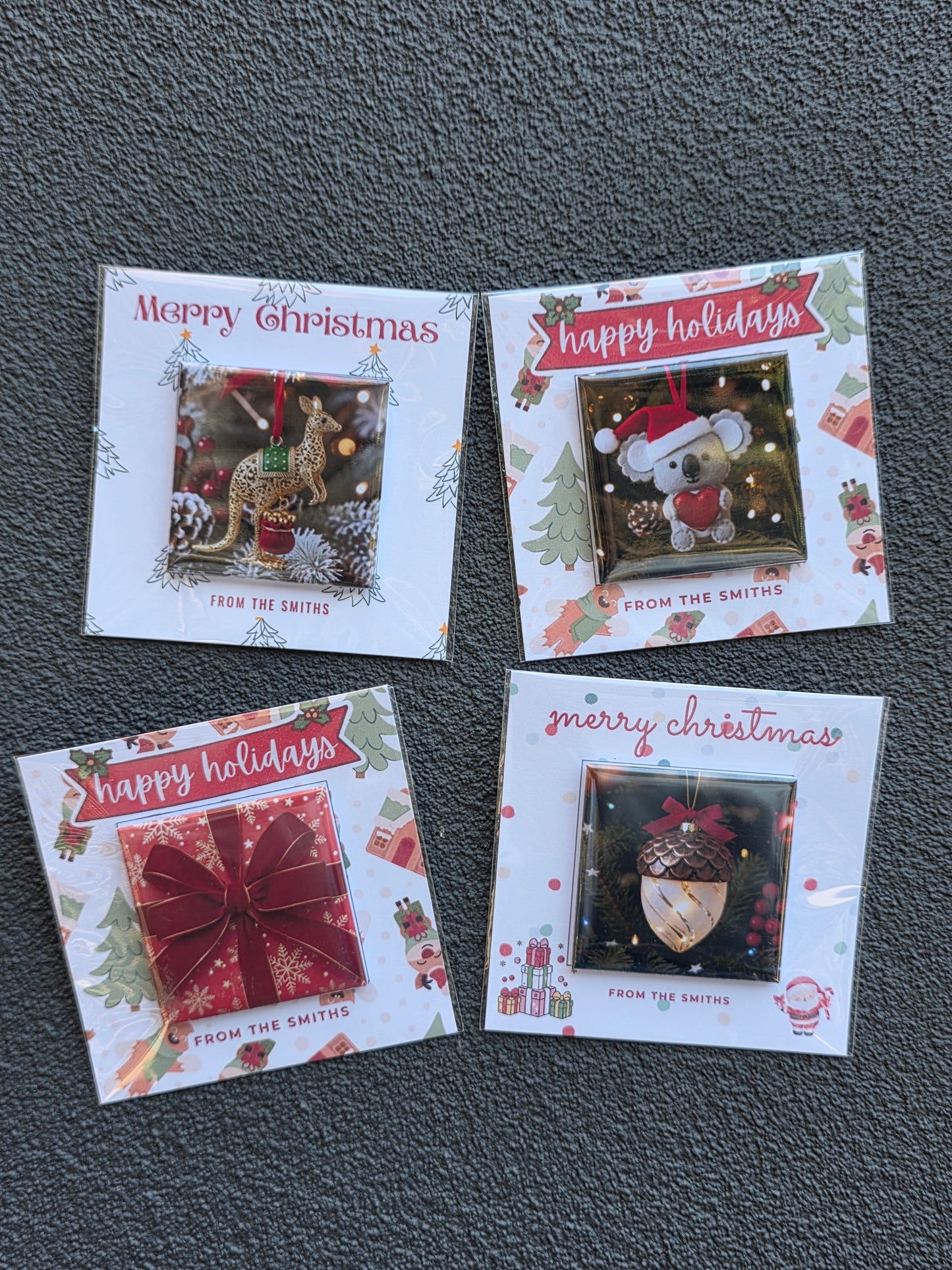 Four Christmas-themed cards with decorative designs on a gray surface
