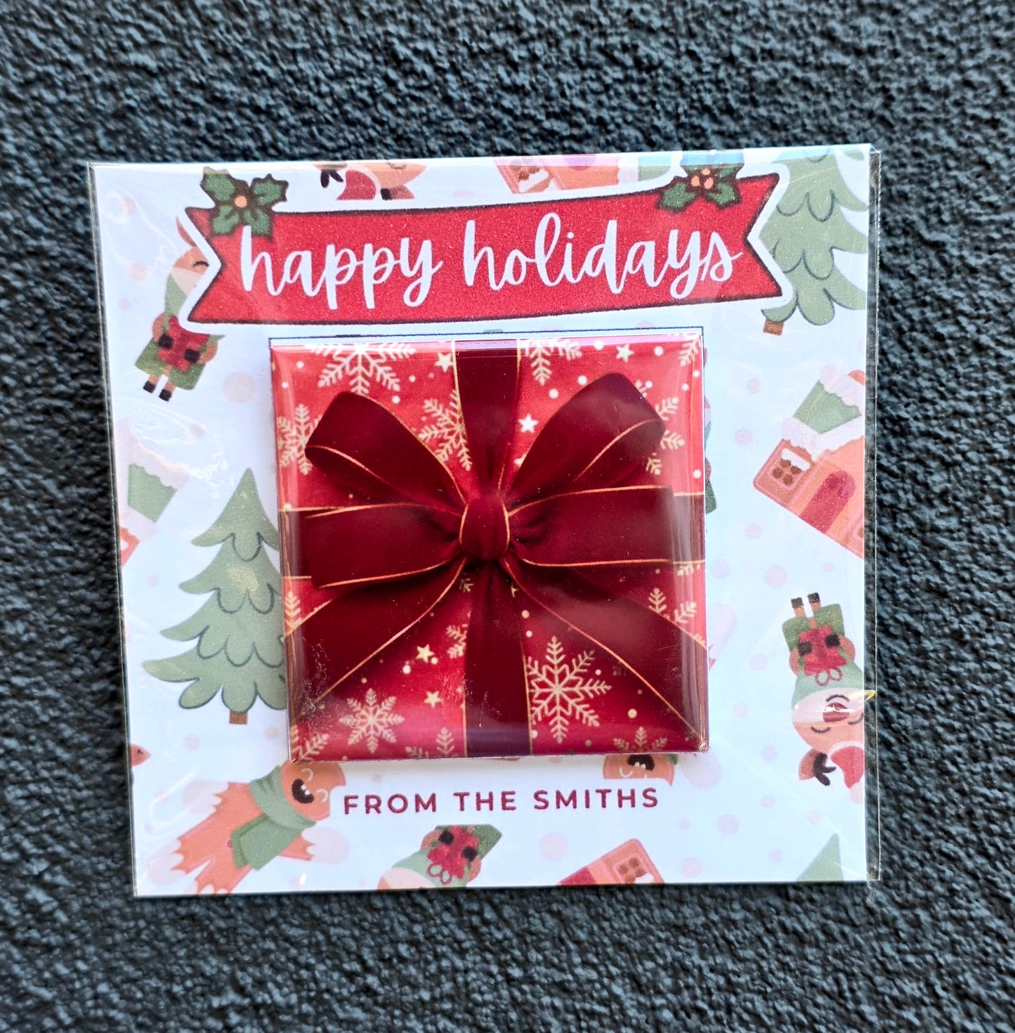 Holiday card with a red bow and 'happy holidays' text on a textured surface
