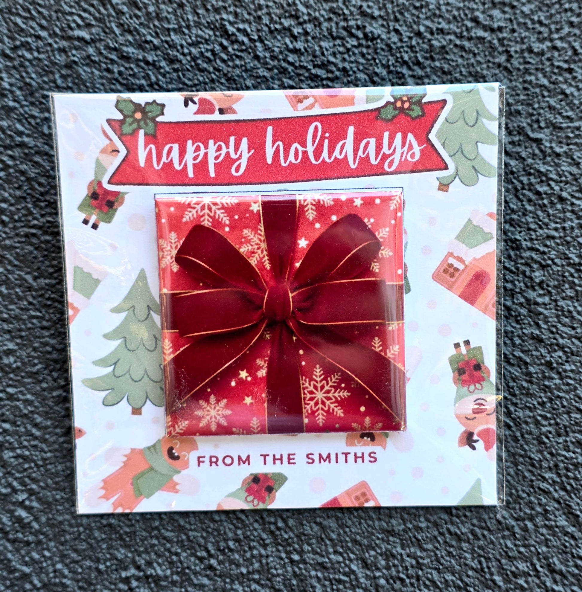 Holiday card with a red bow and 'happy holidays' text on a textured surface