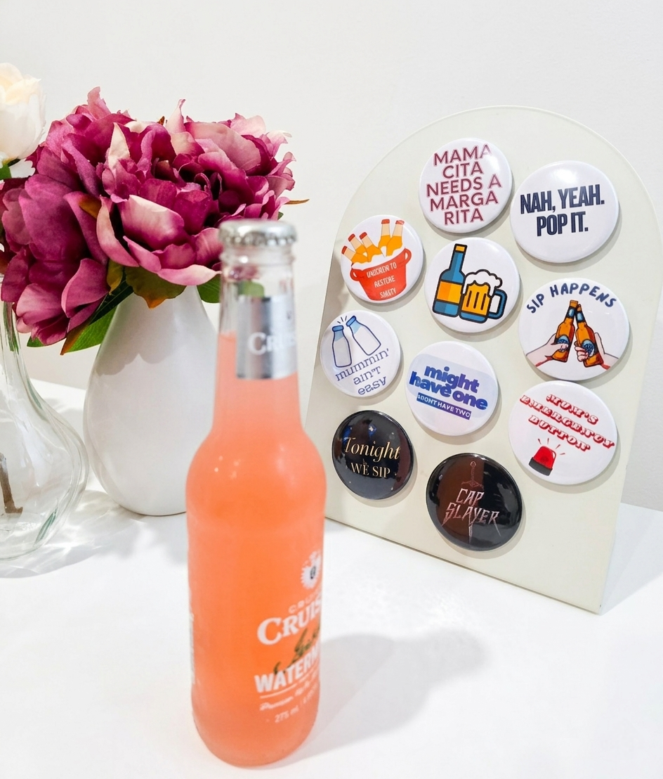Orange soda bottle next to a set of humorous magnetic bottle openers on a white surface with flowers in the background
