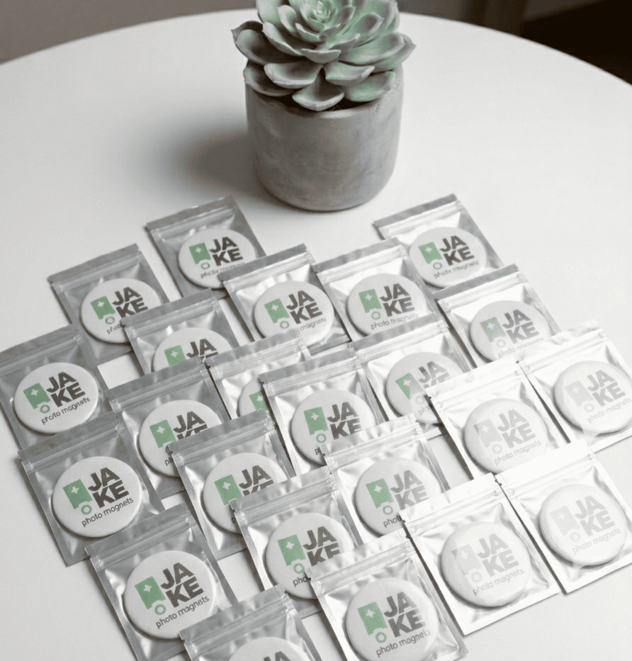 Multiple packages of photo magnets products on a white surface with a succulent plant in the background.