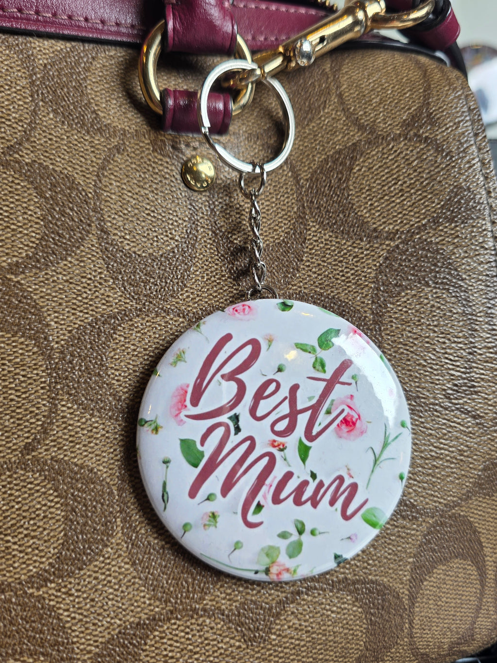 Floral 'Best Mum' mirror key ring attached to a brown leather bag.