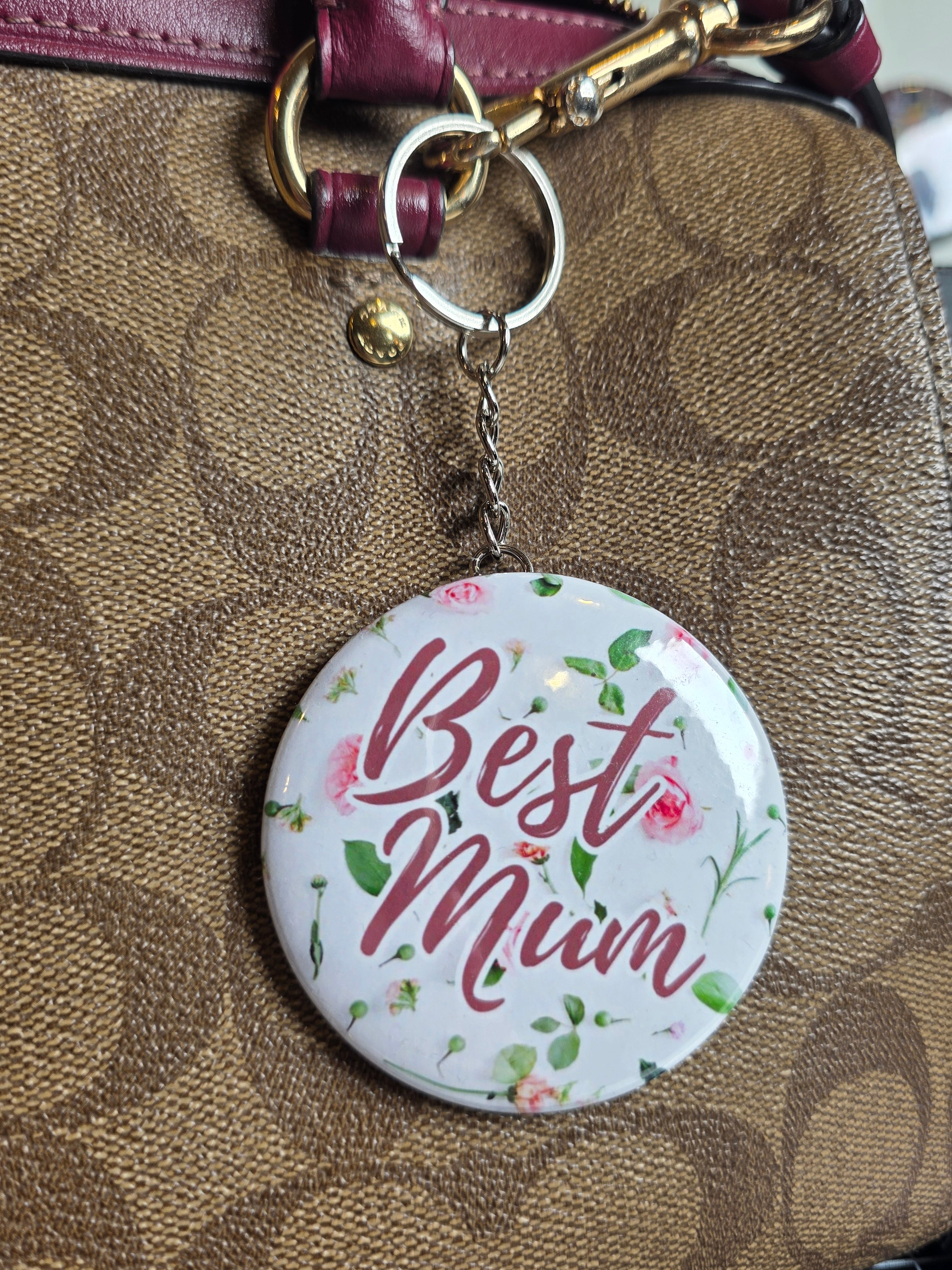 Floral 'Best Mum' mirror key ring attached to a brown leather bag.
