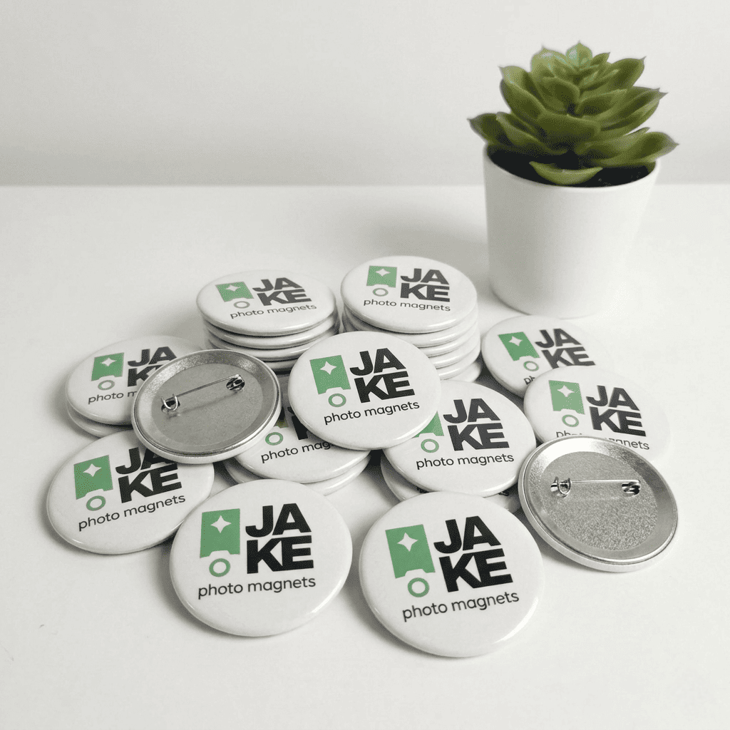 Buttons with 'JAKE photo magnets' text and logo on a white surface with a plant in the background