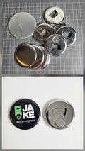 Metal bottle caps with different designs on a grid background, and a close-up of a metal bottle cap with a 'JAKE photo magnets' logo.