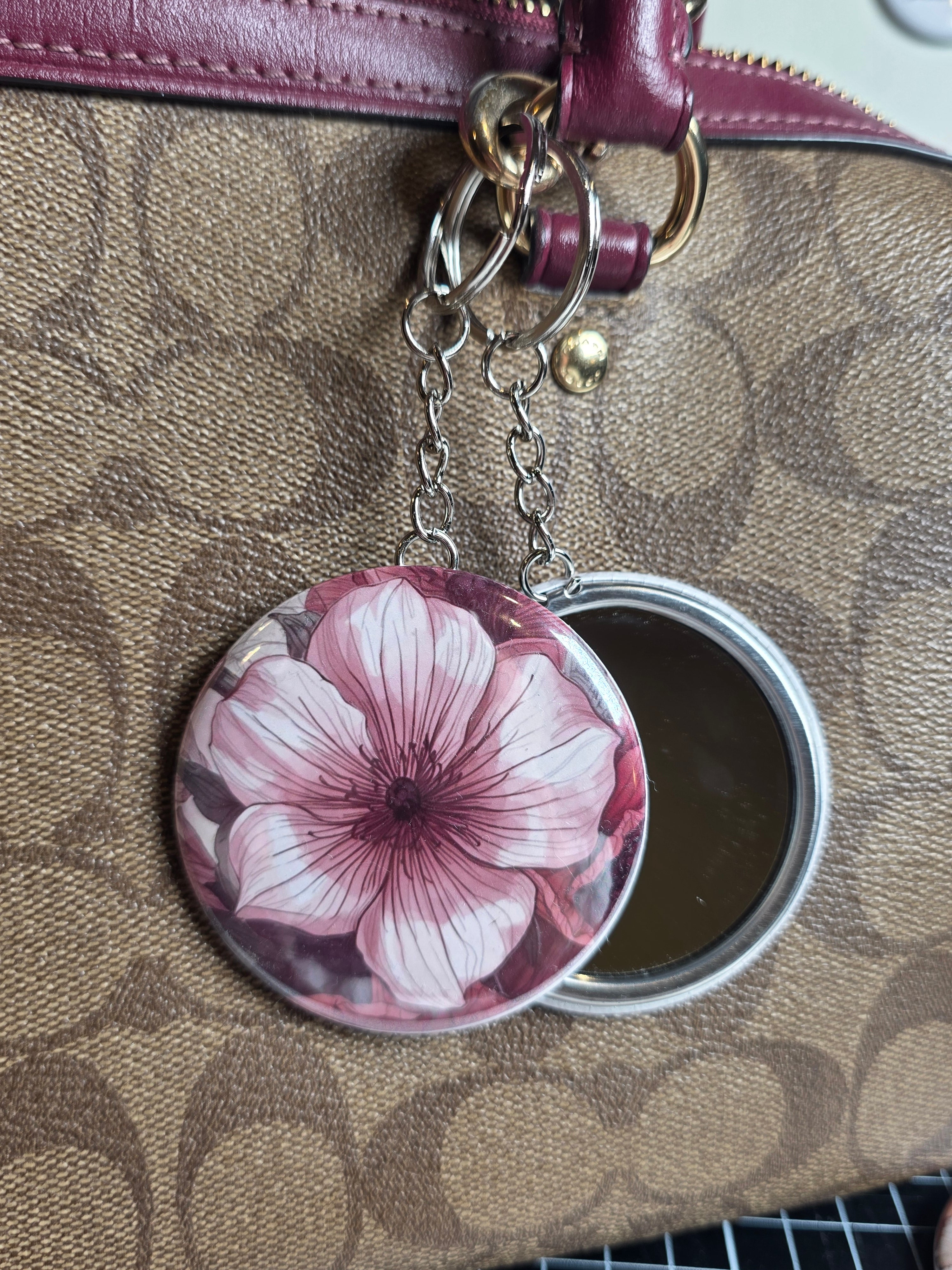 Floral compact mirror key ring attached to a patterned handbag
