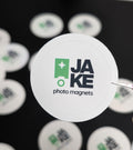 Round white sticker with 'JAKE photo magnets' logo on a black background