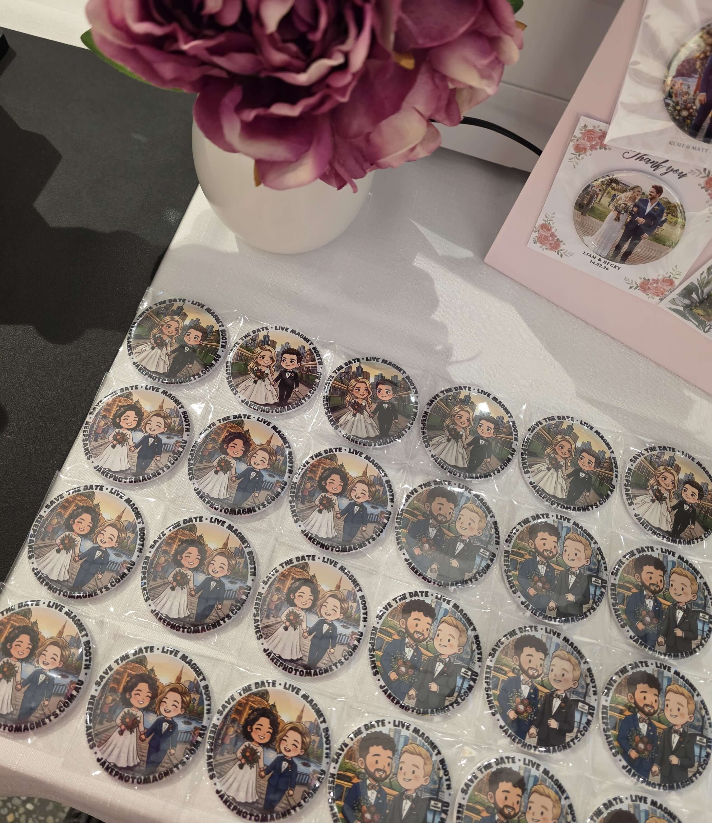 Collection of circular stickers with illustrated characters on a white surface, with a vase of pink flowers in the background.