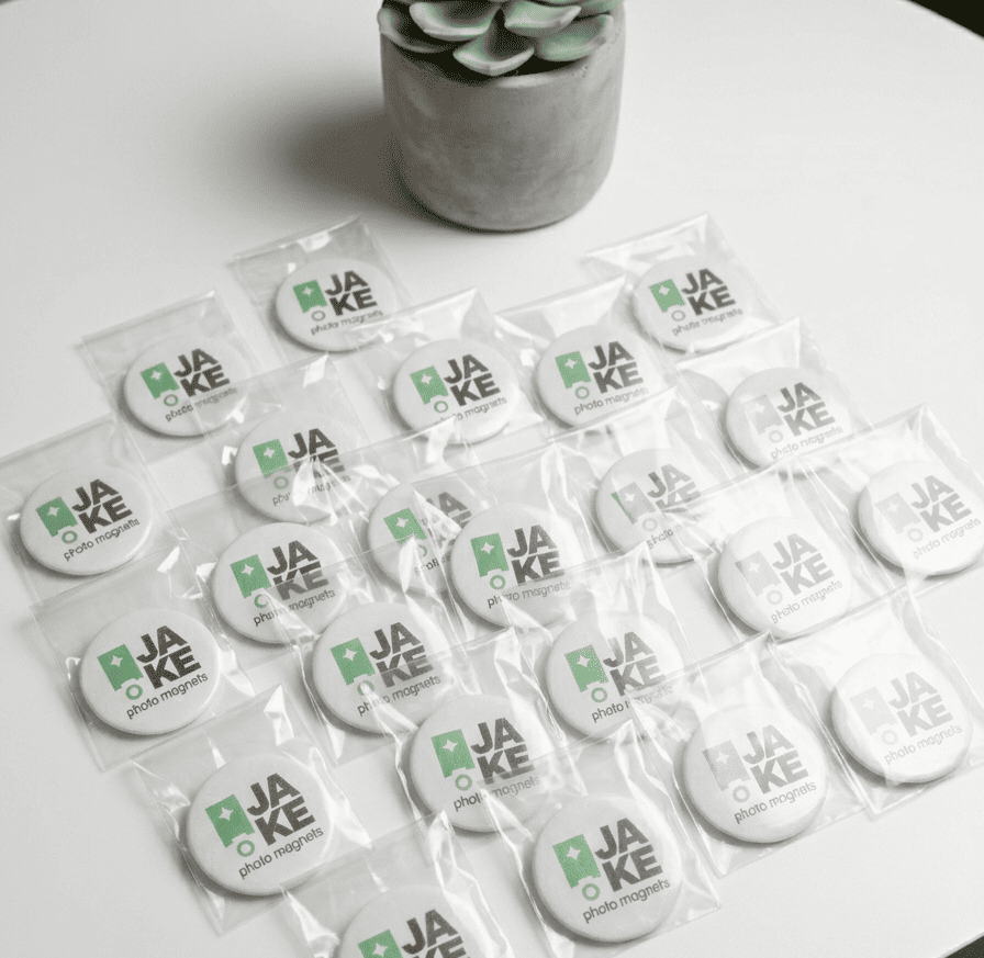 Packaged photo magnets with 'JAKE' branding on a white surface.