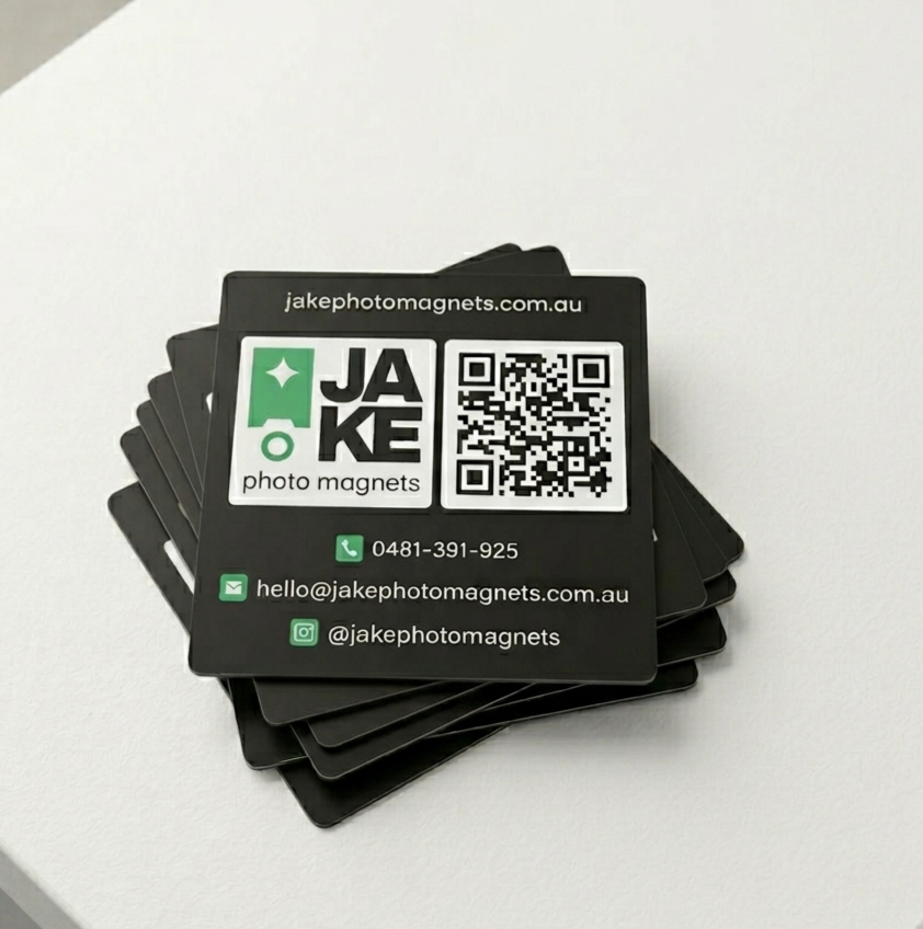 Stack of black business cards with Jake photo magnets branding on a white surface