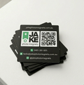 Stack of black business cards with Jake photo magnets branding on a white surface