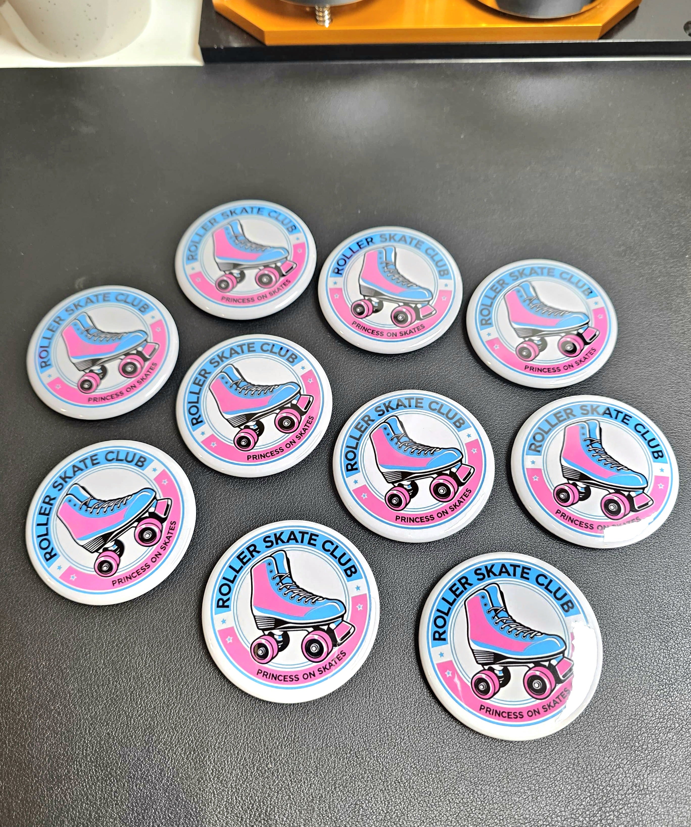 Set of 'Roller Skate Club' badges on a gray surface