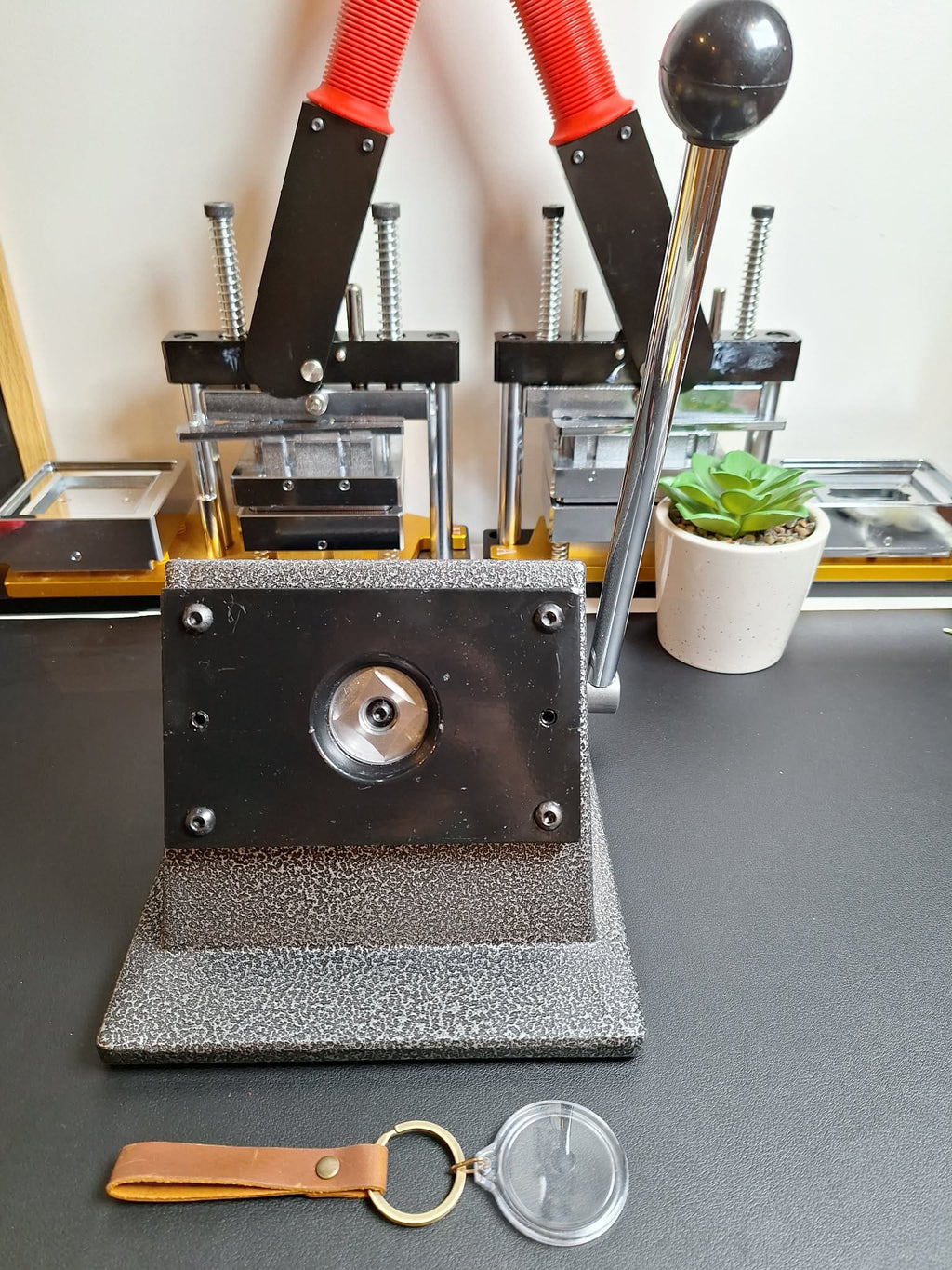 Metal die cutting machine on a desk with a keychain and plastic item nearby
